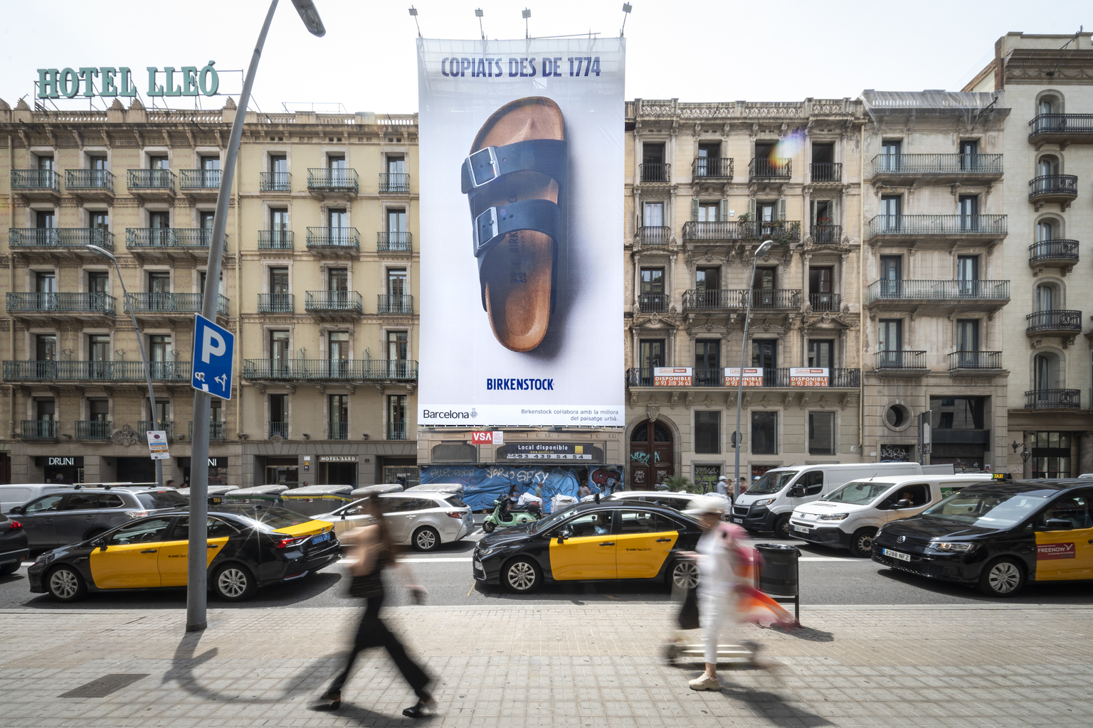 Foto de la Calle Pelai en Barcelona con una lona gigante en la fachada de un edificio con la imagen de Birkenstocl